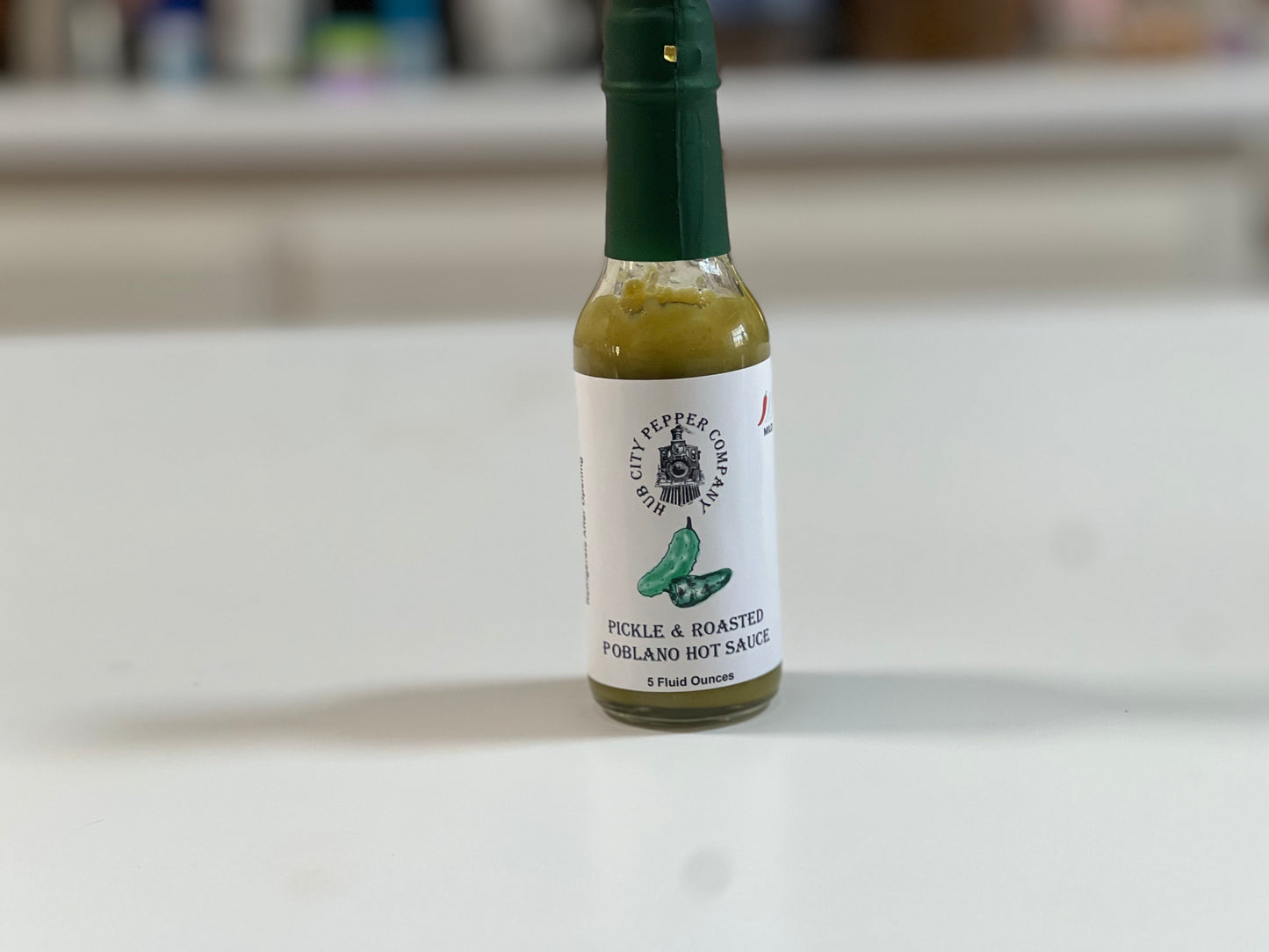 Pickle and Roasted Poblano Hot Sauce Sitting on counter