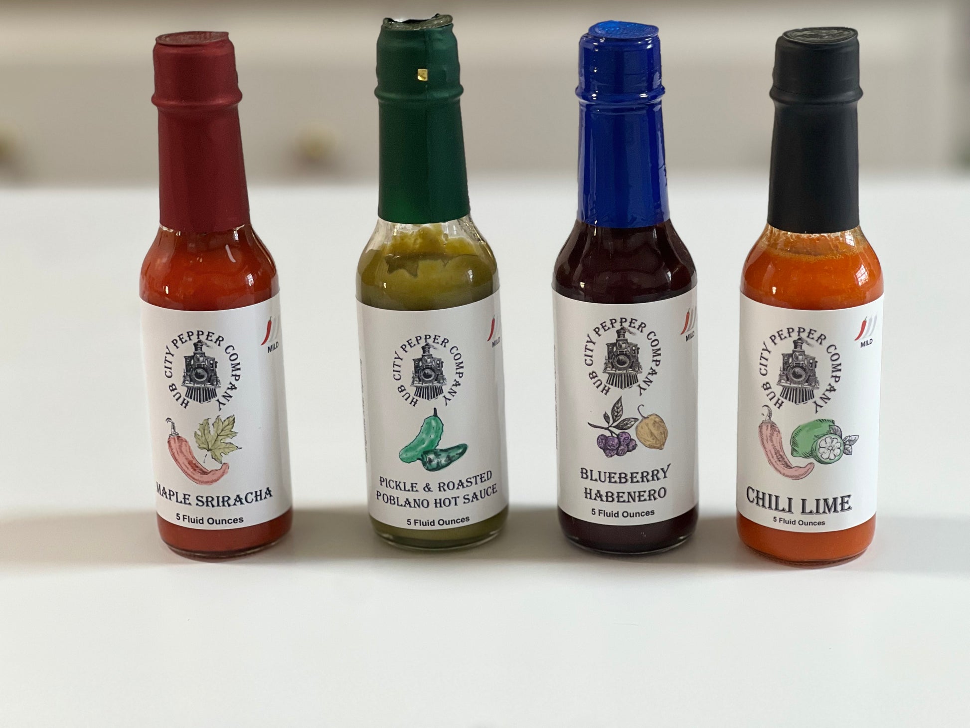 4 Pack of hot sauce flavors. Including Maple Sriracha, Pickle and Roasted Poblano, Blueberry Habenero and Chili Lime flavors. all images are from the front. Spicy and delicious.