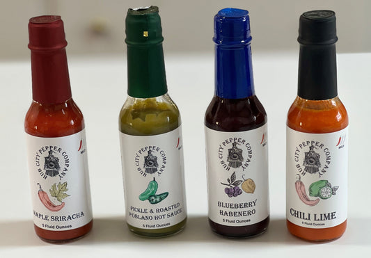 4 Pack of hot sauce flavors. Including Maple Sriracha, Pickle and Roasted Poblano, Blueberry Habenero and Chili Lime flavors. all images are from the front. 